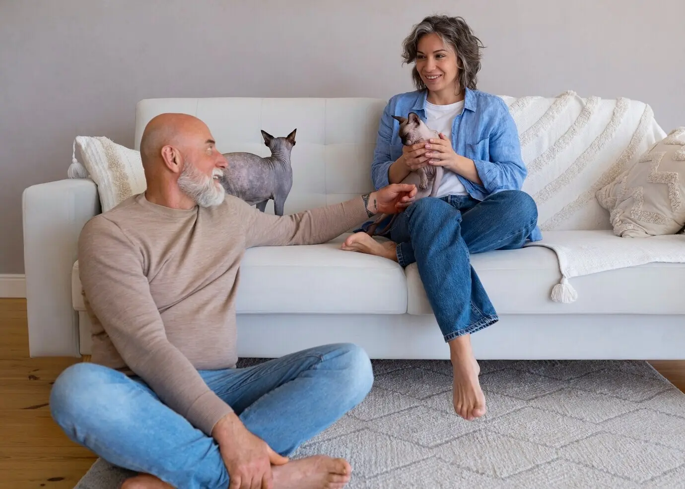 Ganzkörperaufnahme eines Seniorenpaares mit einer Katze zu Hause.